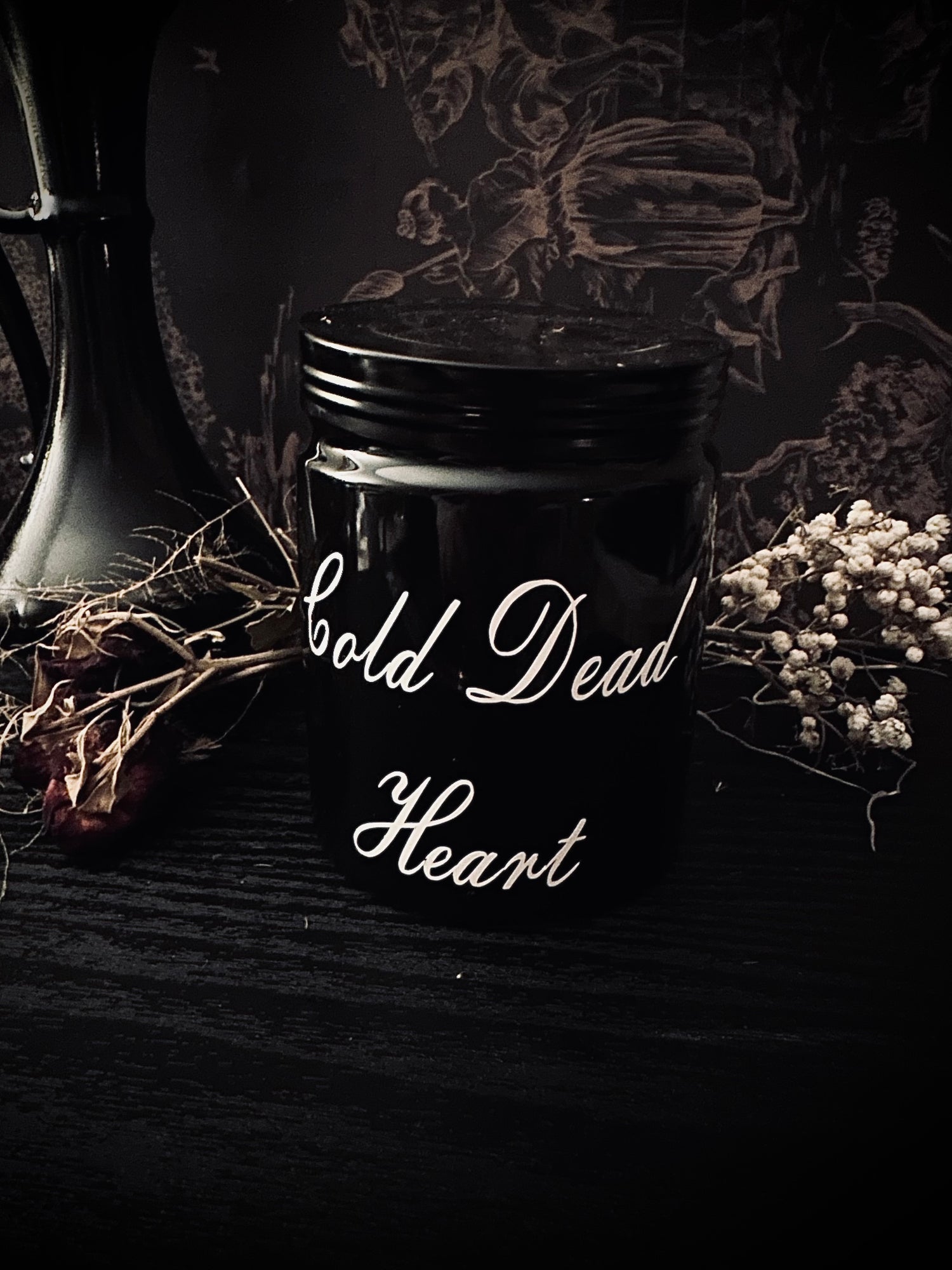 Goth Candles Black jar with 'Cold Dead Heart' text on a dark background with decorative elements.