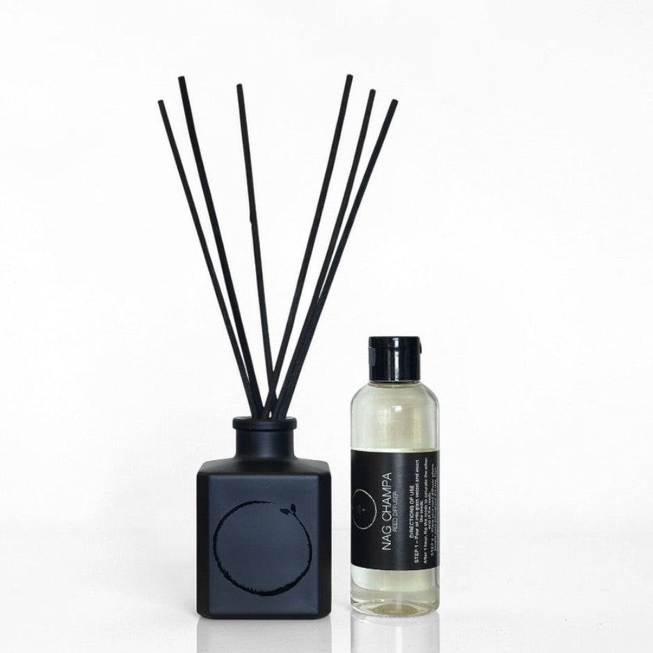 Black diffuser with reeds and a bottle of diffuser liquid on a white background