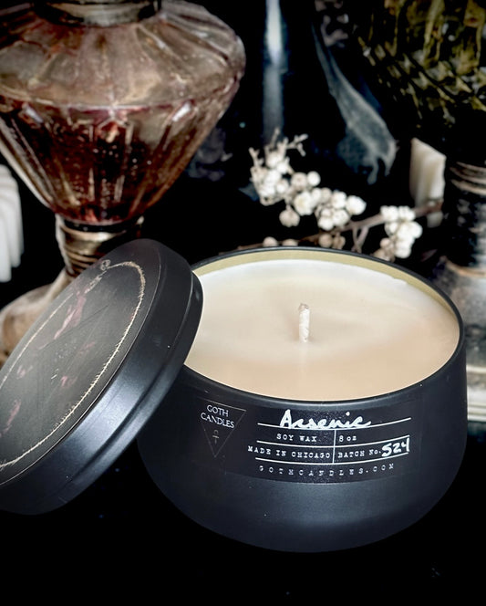 Black candle in a tin with a visible brand name on a dark background