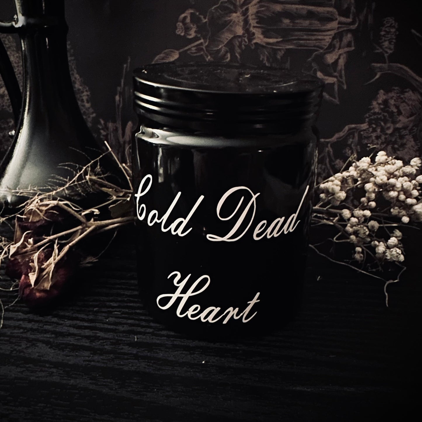 Black jar with 'Cold Dead Heart' text on a dark background with decorative elements.