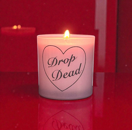Pink candle with 'Drop Dead' text in a heart shape on a red background