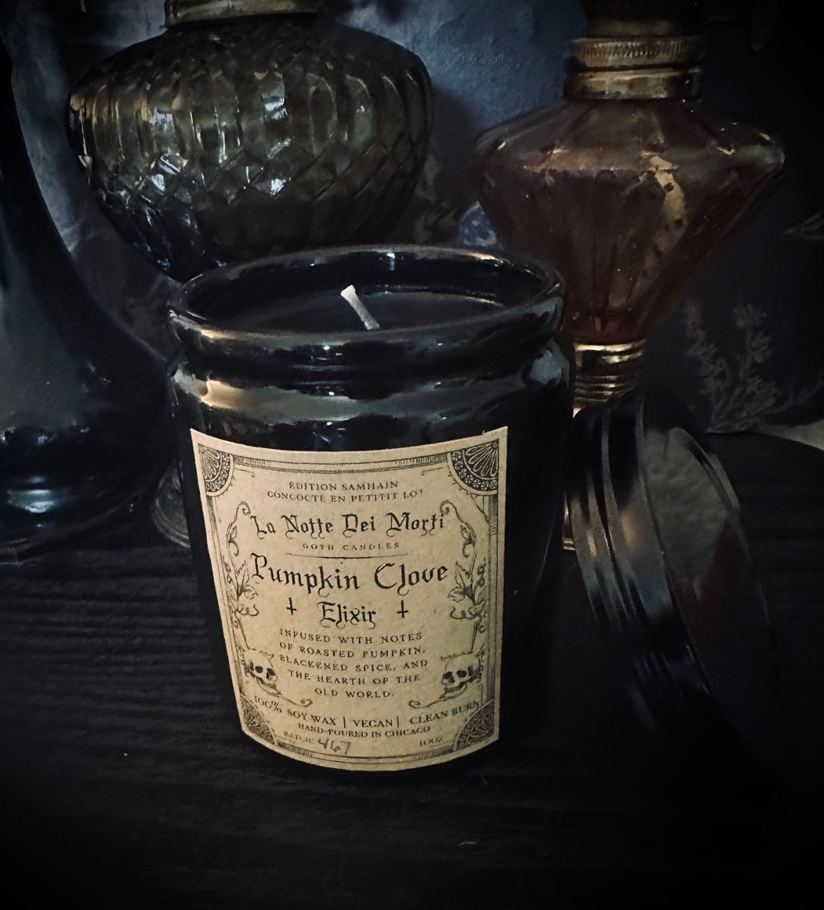 Candle with a label resembling vintage potion bottle design, surrounded by dark bottles.