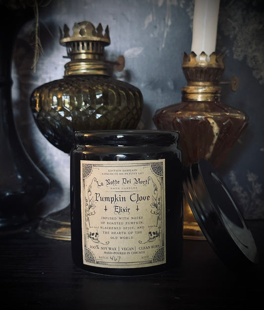 Black candle jar with a label in a dark setting with vintage lamps.