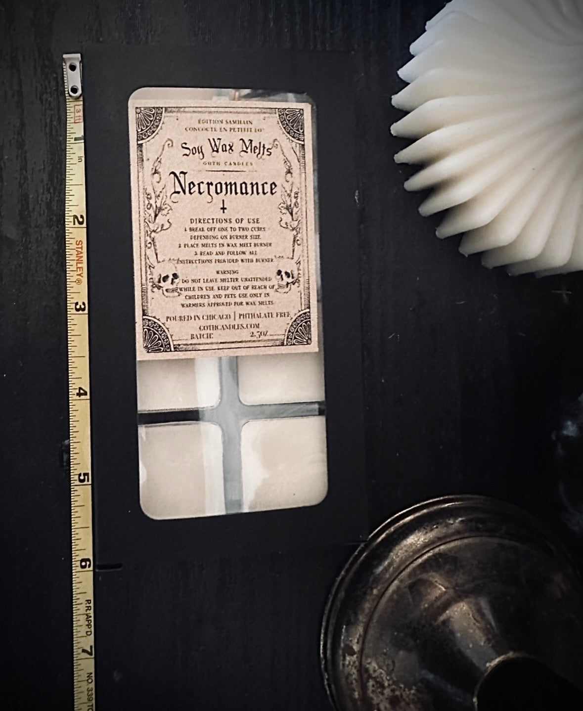Vintage-style necromancer label on a black surface with a ruler for scale.