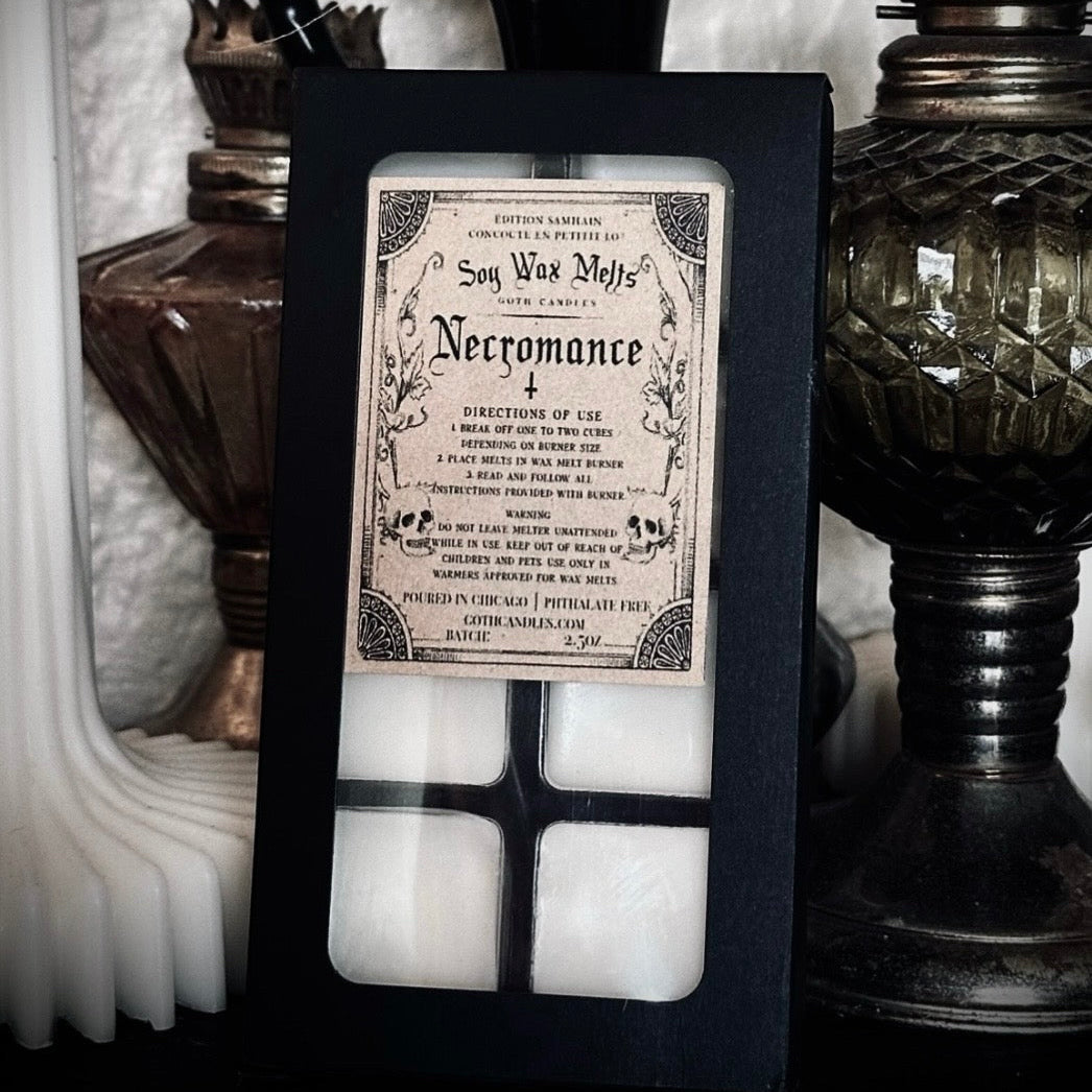 Decorative candle set with a black frame featuring a vintage-style spellbook design, surrounded by dark, vintage-themed decor.