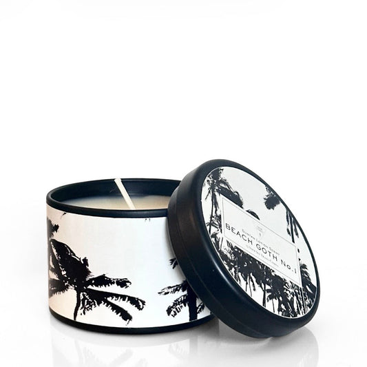Candle in a tin with palm tree design and 'Beach Goth' label on a white background