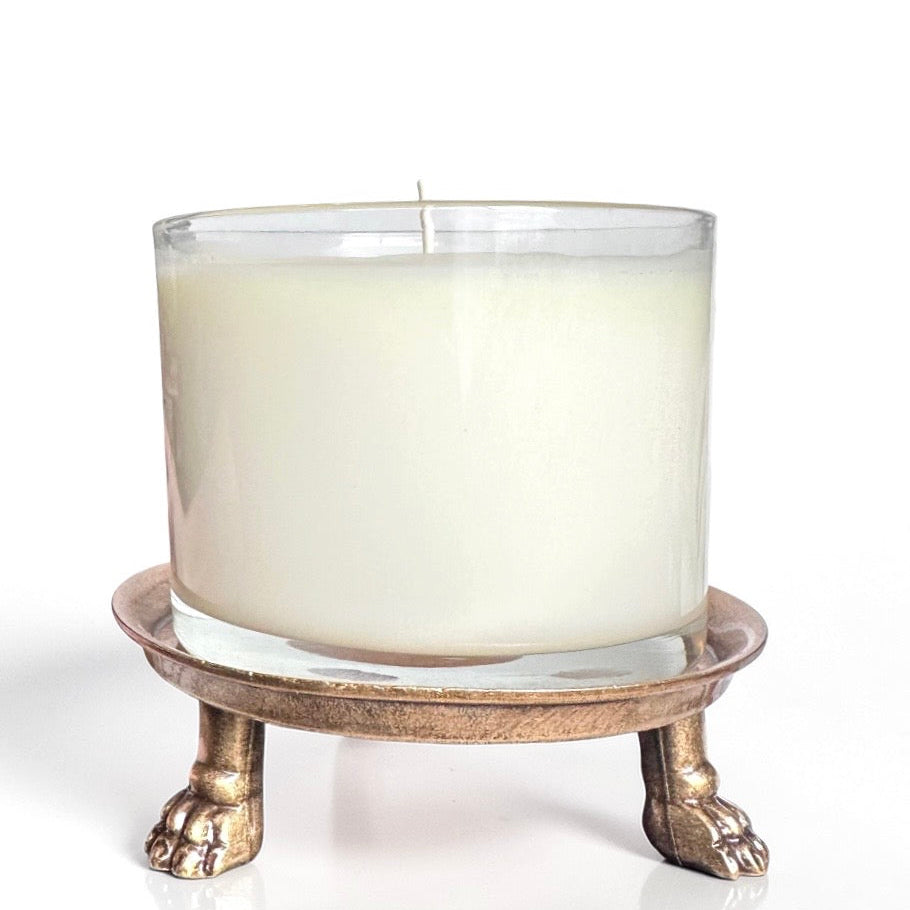 Candle in a glass holder with a decorative metal stand with clawfoot against a white background