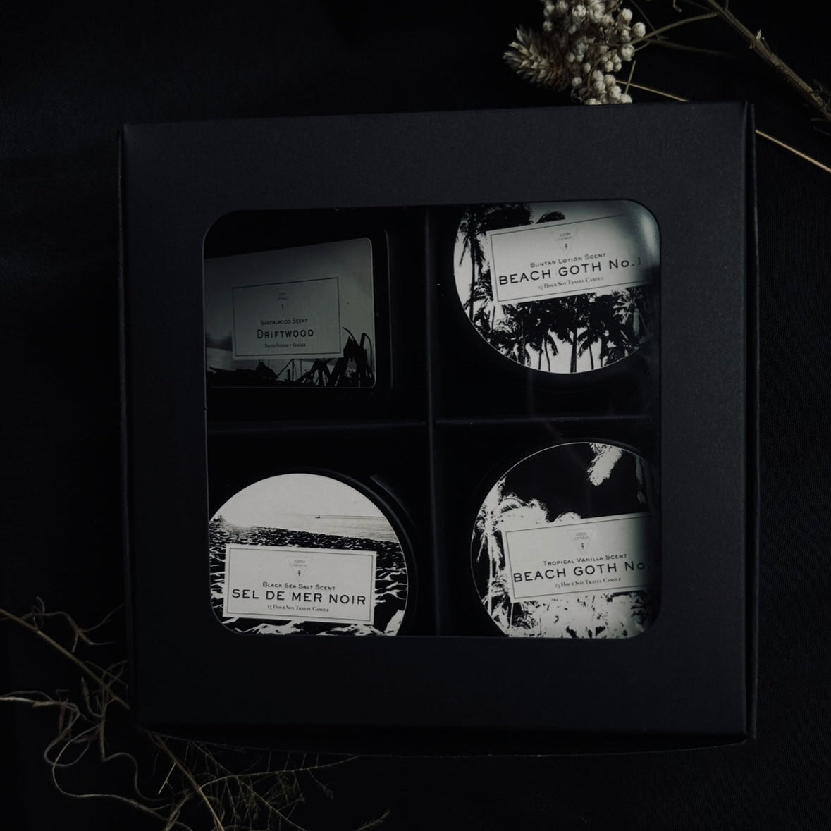 Four candles product labels in a black display box with a dark background.