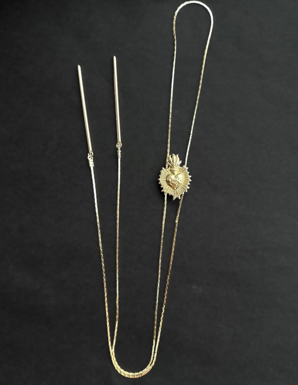 Gold heart bolo necklace on a black background