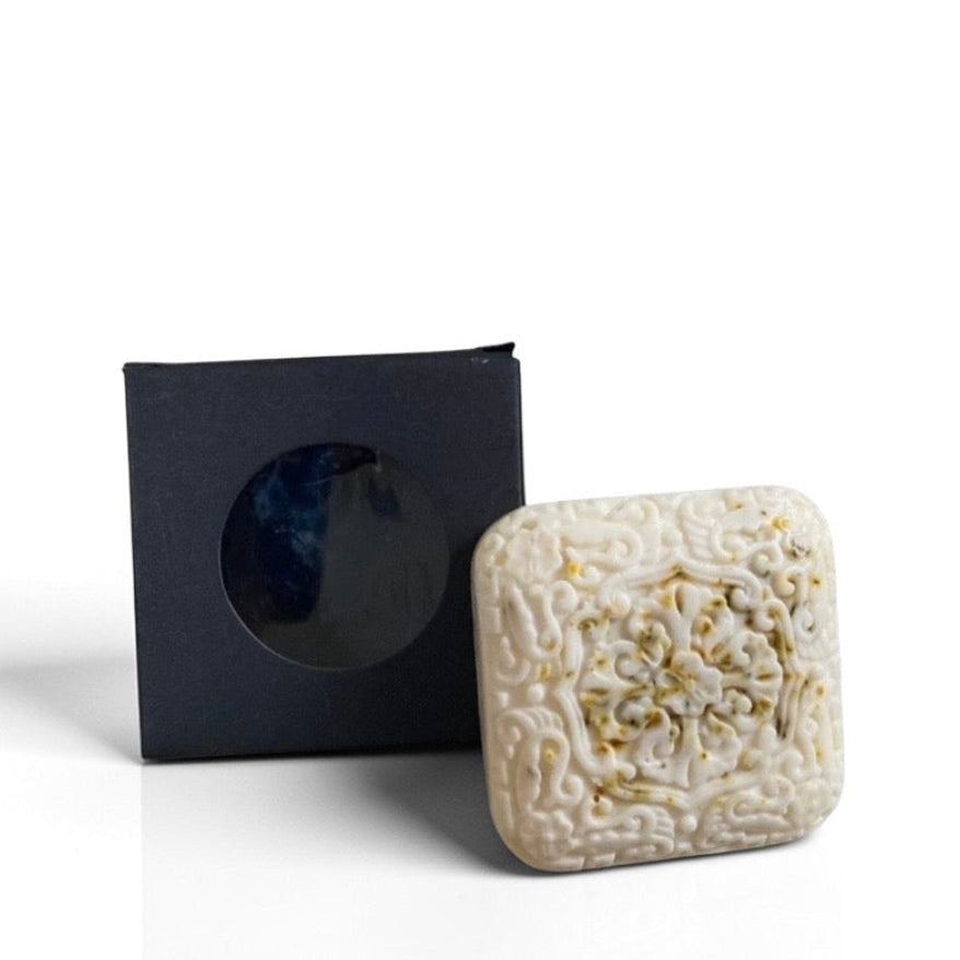 Decorative soap with intricate carvings next to a black box on a white background