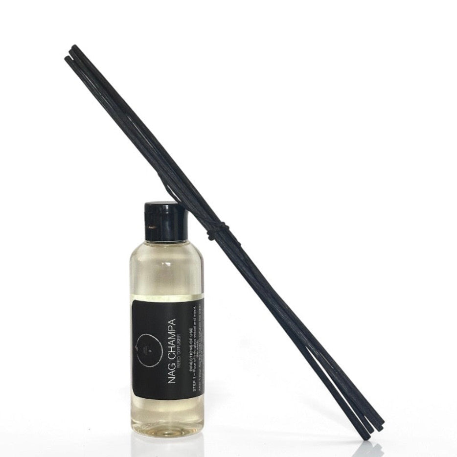 A bottle of Nag Champa diffuser oil with black sticks on a white background