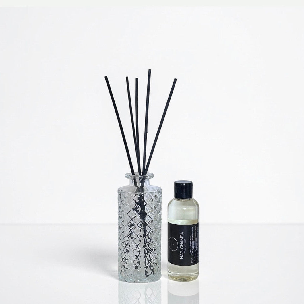 Diffuser bottle with black sticks and smaller bottle on a white background